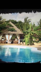 a resort with a swimming pool next to a beach at White bay pianoB in Watamu
