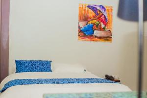 a bedroom with a bed with a painting on the wall at Heritage Hotels Arua in Arua