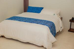 a bed with a blue and white blanket on it at Heritage Hotels Arua in Arua