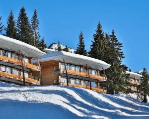 ein Gebäude auf einem schneebedeckten Hügel mit Bäumen in der Unterkunft Mystic Mountain Apartment Chamrousse in Chamrousse