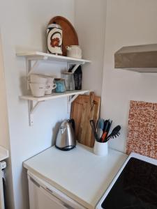 uma cozinha com balcões brancos e prateleiras na parede em Lille bo em Silkeborg