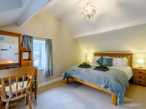 a bedroom with a bed and a chair and a window at 2 bed in Tywyn 83956 in Abergynolwyn