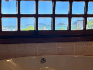 uma banheira na casa de banho com uma janela em Pousada Canajurê em Florianópolis