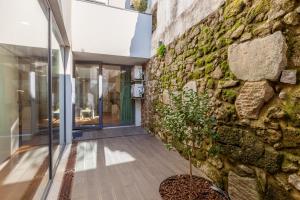 a building with a stone wall and a potted plant at Yellow Lodge - Minho's Guest in Braga