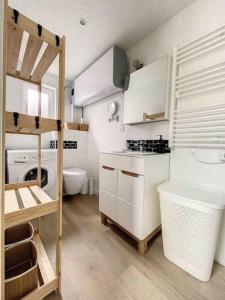 a kitchen with white cabinets and a washer and dryer at Le Wilson Cosy in Dijon