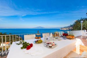 a table with food on top of a balcony with the ocean at Amore Rentals - Villa Giada in Sorrento