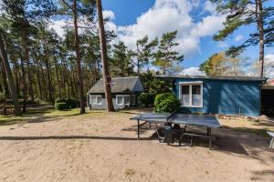 uma mesa de pingue-pongue em frente a uma pequena casa em Ferienhäuser HITTHIM Baabe - Ferienwohnung Gellen em Baabe