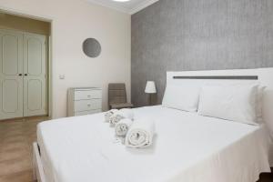 - une chambre avec un lit blanc et des serviettes dans l'établissement Jaune - 50 meters to the beach - Quarteira, à Quarteira