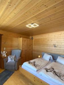Blick Tirol direkt auf der Skipiste في ميترسيل: سرير كبير في غرفة خشبية مع كرسي