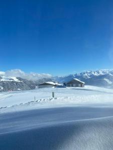 a snow covered field with a house in the distance at Blick Tirol direkt auf der Skipiste in Mittersill