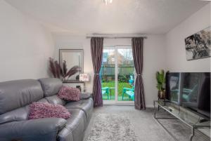 a living room with a couch and a television at WORCESTER Fabulous Cherry Tree Mews self check in dogs welcome , 2 double bedrooms ,super fast Wi-Fi, with free off road parking for 2 vehicles near Royal Hospital and woodland walks in Worcester