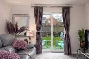 a living room with a couch and a sliding glass door at WORCESTER Fabulous Cherry Tree Mews self check in dogs welcome by prior arrangement , 2 double bedrooms ,super fast Wi-Fi, with free off road parking for 2 vehicles near Royal Hospital and woodland walks in Worcester
