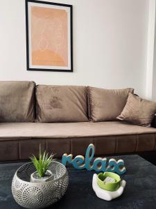 a brown couch sitting in a living room with a plant at BK2 APARTMAN in Kragujevac