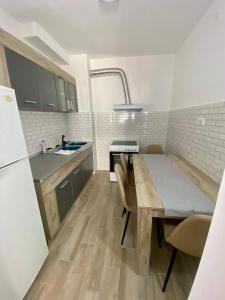 a small kitchen with a wooden table and a refrigerator at BK2 APARTMAN in Kragujevac