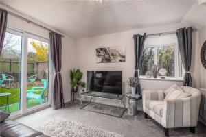 a living room with a couch and a television at WORCESTER Fabulous Cherry Tree Mews self check in dogs welcome , 2 double bedrooms ,super fast Wi-Fi, with free off road parking for 2 vehicles near Royal Hospital and woodland walks in Worcester