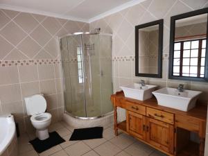 a bathroom with two sinks and a shower and a toilet at Jacobsons Guesthouse in Bloemfontein