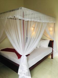 - une chambre avec un lit à baldaquin et des rideaux blancs dans l'établissement Anthony Guesthouse, à Hikkaduwa