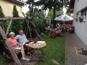 a group of people sitting on a bench in a yard at Willa Pod Jedlicą in Ciechocinek