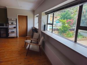 Jacobsons Guesthouse في بلومفونتين: غرفة معيشة مع نافذة وكراسي كبيرة