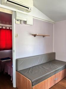 Cama en habitación con cortina roja en Bungalows Zaragoza Camping, en Zaragoza