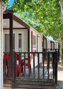 eine Terrasse mit roten Stühlen und ein Haus in der Unterkunft Bungalows Zaragoza Camping in Saragossa