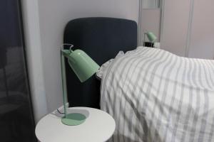 a green lamp on a table next to a bed at joli 2 pièces avec cour privée in Lons-le-Saunier