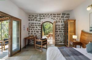 a bedroom with a stone wall with a bed and a desk at Jungle stay by Bilwa Estate in SanivÄrsante