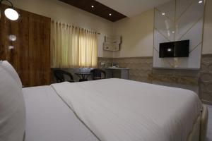 a bedroom with a large white bed and a television at Palm Springs Beach Resort - Gorai in Mumbai