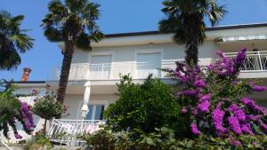 a building with palm trees and purple flowers at Apartments Fink in Portorož
