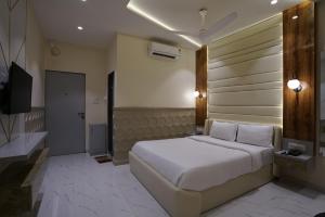 a bedroom with a white bed and a television at Palm Springs Beach Resort - Gorai in Mumbai