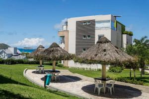 弗洛里亚诺波利斯Suas férias com todo conforto PÉ NA AREIA的建筑物前摆放着一组桌子和草伞。