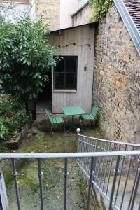 a patio with a green table and two benches at joli 2 pièces avec cour privée in Lons-le-Saunier