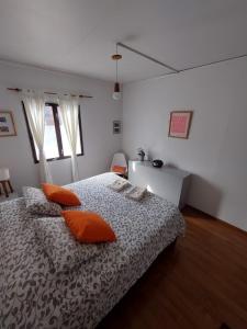 um quarto com uma cama com almofadas laranja em Habitación con Baño Privado - Frigo bar y sector para desayunar - Sin cocina em Ushuaia
