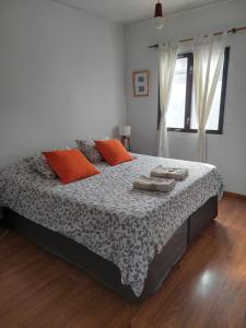 um quarto com uma cama com almofadas laranja em Habitación con Baño Privado - Frigo bar y sector para desayunar - Sin cocina em Ushuaia