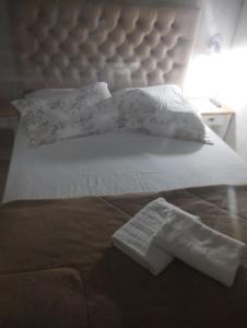 uma cama branca com uma grande cabeceira de cama e uma toalha branca em Pousada águia da serra em Gramado