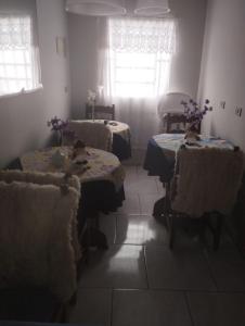una habitación con 2 mesas y sillas con flores. en Pousada águia da serra, en Gramado