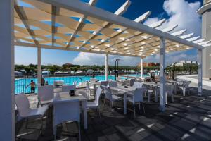 a patio with white tables and chairs and a pool at Camping Internazionale - Sottomarina di Chioggia in Chioggia