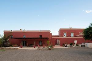un gran edificio rojo con un patio delante de él en Antica Masseria le Monache en Grottaglie