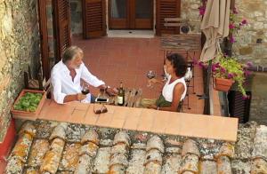 San GusmèにあるBorgo San Gusmèのワインを飲みながらテーブルに座る2名