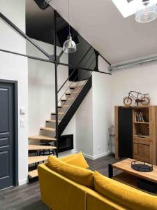 a living room with a yellow couch and stairs at Loft relais Cœur de France in Vierzon