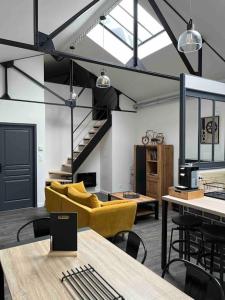 a living room with a yellow couch and a staircase at Loft relais Cœur de France in Vierzon