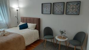 a bedroom with a bed and two chairs and a table at Azulejo Apartment in Novi Beograd