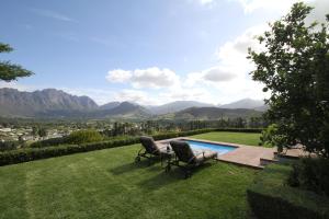 two chairs sitting in the grass next to a swimming pool at The Vineyard Cottage by L' Amitie Estate in Franschhoek