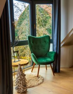 una silla verde sentada frente a una gran ventana en AMAO-Green I 90qm I Zentrum I Maisonette I Dachterrasse I King-Size Boxspringbetten I EuropaPark, en Lahr