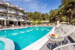 a pool at a hotel with chairs and umbrellas at Green Bay in Limenaria