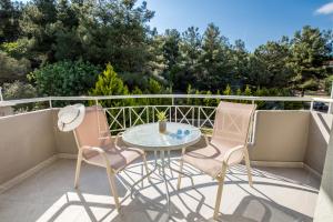a patio with two chairs and a table on a balcony at Green Bay in Limenaria