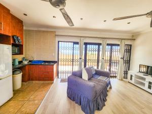 a living room with a couch and a kitchen at Spekboom Beach Apartments in Jeffreys Bay