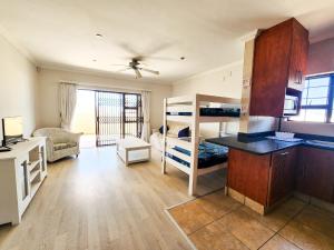 a room with a kitchen and a living room with bunk beds at Spekboom Beach Apartments in Jeffreys Bay