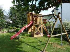 a playground in a yard with a red slide at Casa Graf in Bad Emstal