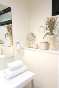 - une salle de bains pourvue de serviettes blanches et de fleurs sur une étagère dans l'établissement Le Parc du Château, à Hermonville